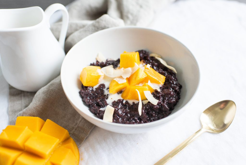 Black Rice Hazelnut Porridge topped with mango and dried coconut chips by Karlene Karst