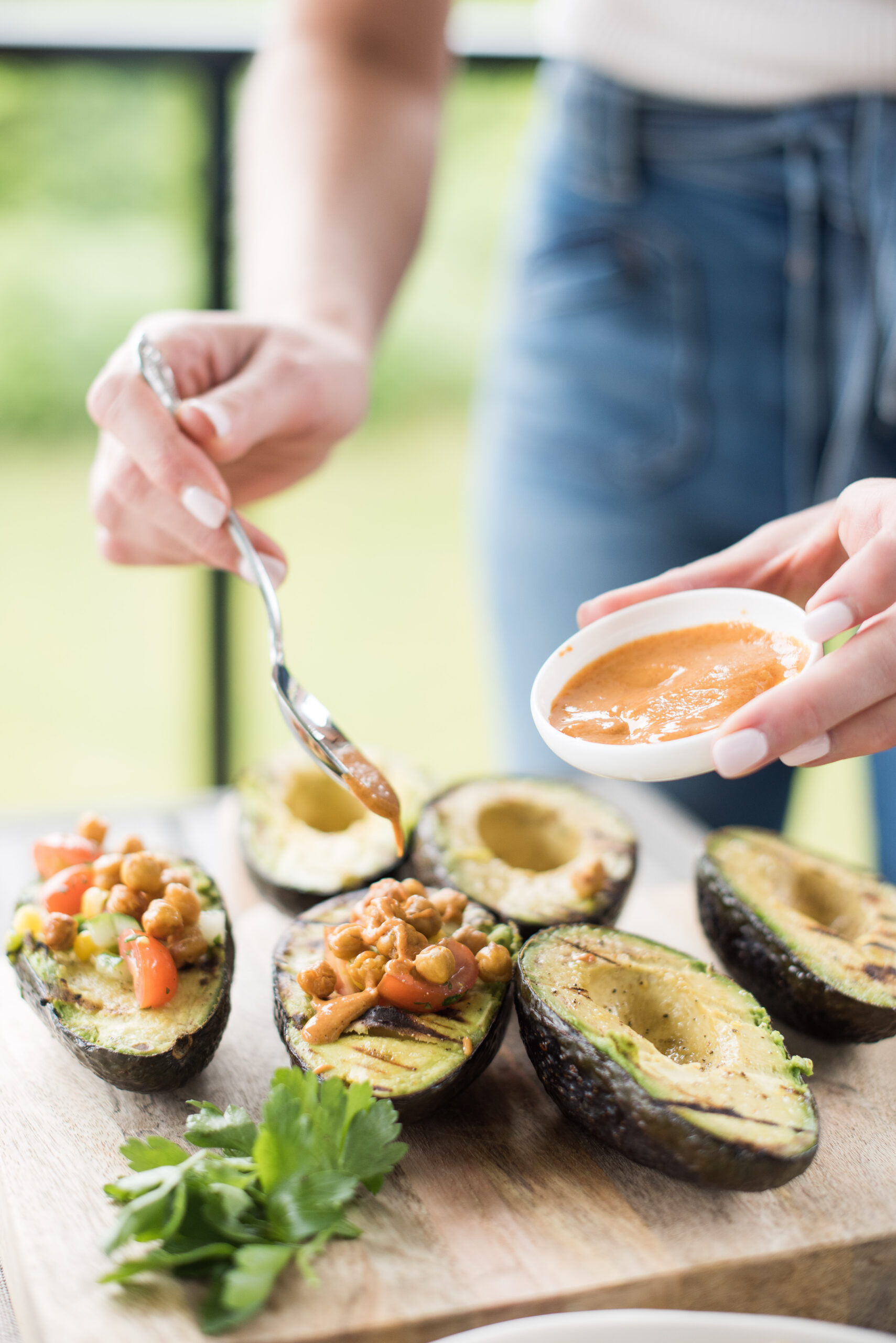 Karlene Karst topping grilled avocado boats with tahini dressing